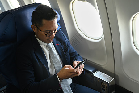 在飞行期间使用机上无线连线的智能电话检查消息的自信商商客乘客旅客人数图片