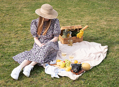 穿着蓝裙子和草帽的年轻女子 在野餐上休息着水果女性喜悦生活方式假期金发女郎季节公园篮子女孩幸福图片