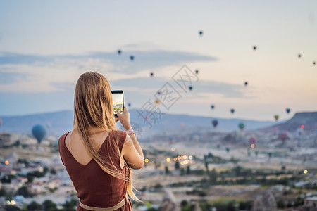 在土耳其卡帕多细亚看热气球的女游客 土耳其概念中的快乐旅行 山顶上的女人享受美妙的景色冒险蜜月日出蓝色航班悬崖日落旅游假期空气图片