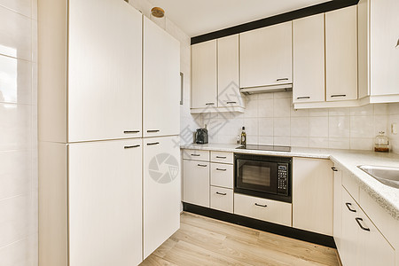 一个白色厨房 有白色柜子和黑柜子烤箱用具修剪木头风格内阁奢华器具家具家电图片