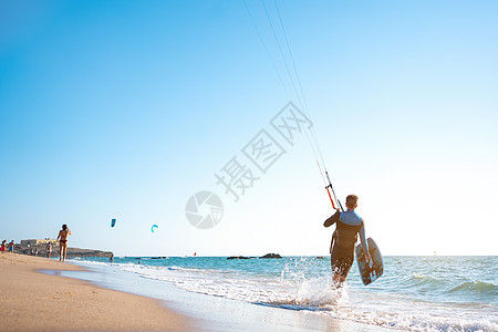与他的董事会和风筝一起在海滩上行走男人自由木板海浪行动天空潜水海岸运动冲浪者图片