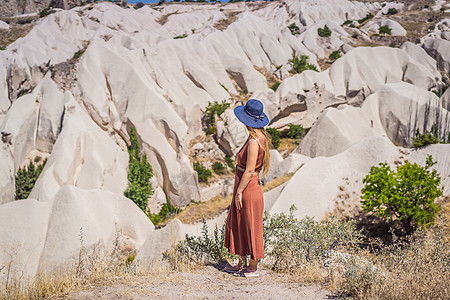 在土耳其卡帕多西亚的Goreme附近 年轻女性用岩石层和童话洞穴探索山谷烟囱建筑公园冒险沙漠旅游爬坡火鸡砂岩内夫图片