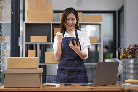 美丽的亚洲女商务人士的企业家使用笔记本电脑在线工作 并在家里庆祝她的工作成功快乐和幸福 小企业创业概念生意店铺女士营销产品命令金图片