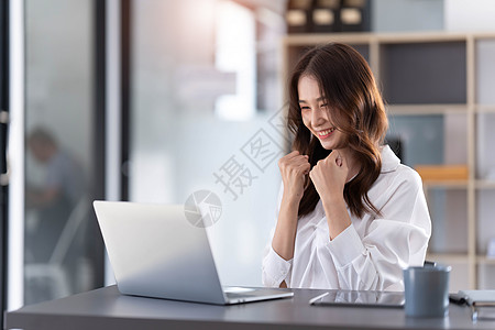 使用笔记本电脑的美丽的亚洲女性 令人振奋和以商业成功的好消息来庆祝 小生意启动概念 笑声技术成就优胜者学生成人胜利互联网人士乐趣图片