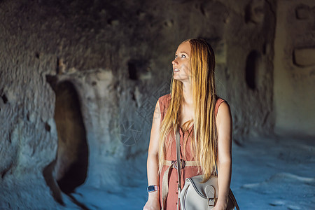 在土耳其卡帕多西亚的Goreme附近 年轻女性用岩石层和童话洞穴探索山谷女孩石头历史女士编队公园建筑学场景爬坡火鸡图片