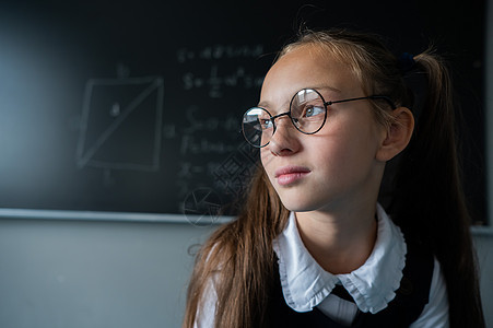 教室里一个戴眼镜的天主教女孩的肖像 女学生在黑板上回答粉笔相机课堂考试学生童年老师公式青年学校图片