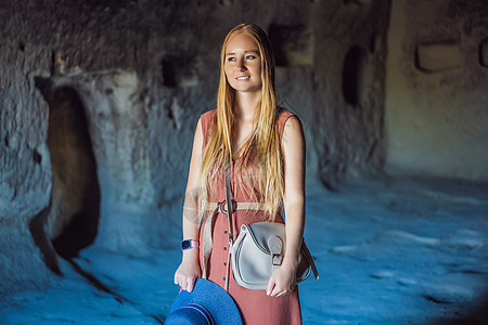 在土耳其卡帕多西亚的Goreme附近 年轻女性用岩石层和童话洞穴探索山谷编队地标远足游客建筑地质学火鸡旅行爬坡砂岩图片