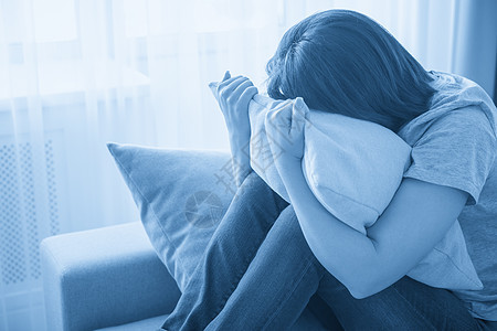坐在沙发上拥抱枕头 孤独和悲伤的悲哀女孩沉思女士女性困惑压力软垫蓝色眼睛长椅疼痛图片