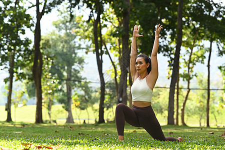 有吸引力的体育女运动员练习瑜伽 站在勇士队中 在公园绿草上摆姿势图片