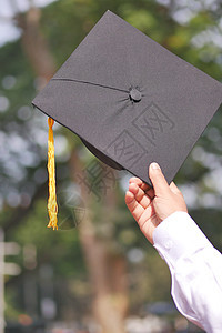 学生在黄背景的入门成功期间手握着帽子庆典黑色教育仪式学习灯光研究生证书男性大学图片