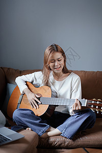在沙发上弹吉他 度假时放松压力的年轻亚洲女人的肖像教育个性青少年家庭生活细绳笔记本学习公寓社交电脑图片