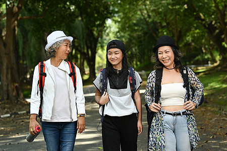 两位微笑着的中年妇女和少女在公园一起走过公共公园的画面图片