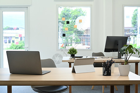 木桌上配有笔记本电脑 文件和各种办公用品的现代办公室内部图片
