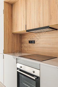 模块化厨房家具片断的特写镜头由木头制成 现代舒适的厨房内部配有内置于大理石台面的电器 抽油烟机隐藏在炉子和烤箱上方的橱柜中图片
