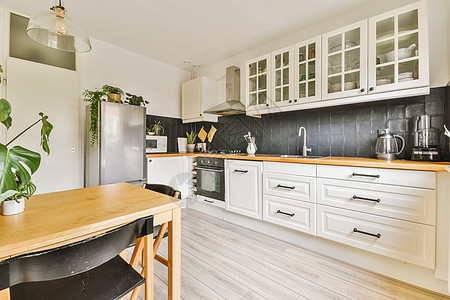 一个有白柜子和木桌的厨房风格财产装饰器具烤箱工艺橱柜奢华公寓木头图片