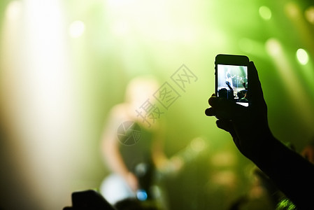 一个用摄像电话拍摄自己最爱的乐队的人 拍了一部摄影机节日演出音乐会灯光人群夜店派对青年团体产业图片