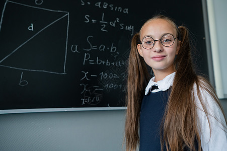 教室里一个戴眼镜的天主教女孩的肖像 女学生在黑板上回答瞳孔数学课堂教育女性孩子测试快乐青年导师图片