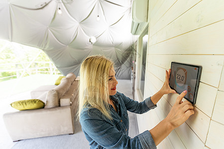 年轻女子在豪华的圆顶帐篷中用数字平板电脑控制家里的灯光 智能家居的概念和移动设备的灯光控制界面创新房间力量客厅房子女性自动化互联图片