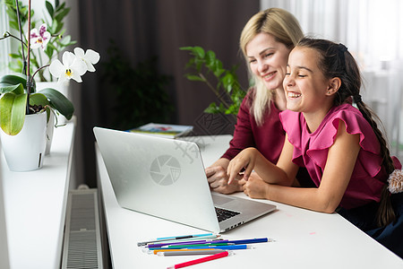 美丽的年轻母亲帮助她的女儿做家庭功课 并给女儿做家庭作业家庭作业妈妈女性两个人幸福电脑女士孩子们技术成人图片