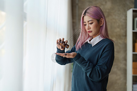 亚裔年轻女性在家感到悲哀和孤独 吃药的女性图片