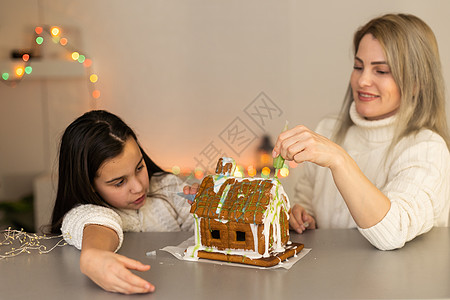 母亲和女儿做姜饼饼干店 在家中装饰 圣诞节的构想父母帽子房子面包装潢食物庆典传统女孩厨房图片