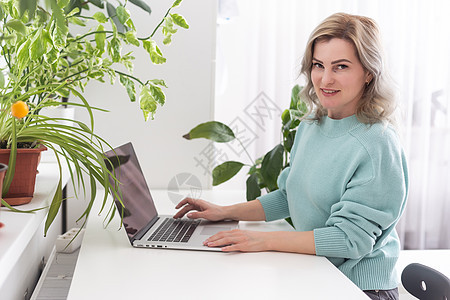 积极的年轻女性在家里使用笔记本电脑进行视频会议 与室内植物的舒适家庭内部 远程工作 商业 自由职业者 在线购物 电子学习概念黑发图片