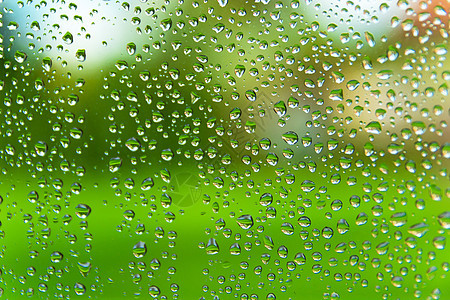 窗玻璃上的雨滴 在绿色户外背景上图片