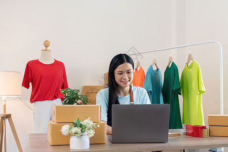 年轻成功的亚洲女性通过开店和网上销售做服装生意 她使用手提电脑 在线销售营销交付 中小企业电子商务电话营销概念图片