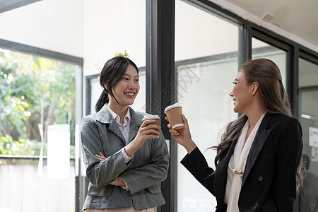 不同的员工在休息时间聊天 在现代办公室散步 戴着眼镜的亚洲女商务人士分享想法 与同事讨论项目 愉快地交谈公司女性咖啡雇员朋友们职图片