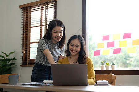 两位年轻的亚洲女商务人士在办公室交谈 咨询 讨论与新创业项目创意演示的合作分析计划营销和投资职员代理人公司同事经理女性团队工人招图片