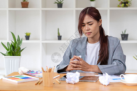 疯狂愤怒的亚洲年轻女性平面设计师或女商务人士 桌上放着一张皱巴巴的纸 对她的工作不满意 向老板抱怨 遇到了工作问题手势商务办公室背景图片