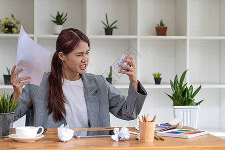 疯狂愤怒的亚洲年轻女性平面设计师或女商务人士 桌上放着一张皱巴巴的纸 对她的工作不满意 向老板抱怨 遇到了工作问题人士手势桌子职图片