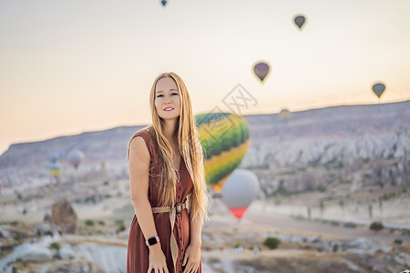 在土耳其卡帕多细亚看热气球的女游客 土耳其概念中的快乐旅行 山顶上的女人享受美妙的景色日出冒险空气女性蜜月家庭女孩吸引力男人蓝色图片