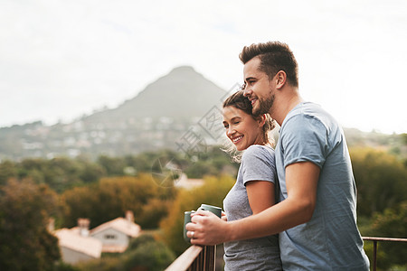 这是我们快乐的地方 一对恩爱的年轻夫妇早上站在家里的阳台上喝咖啡图片