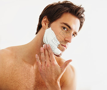 聪明的年轻人在脸上涂剃须膏 一个英俊的年轻人在脸上涂抹剃须膏的特写肖像图片