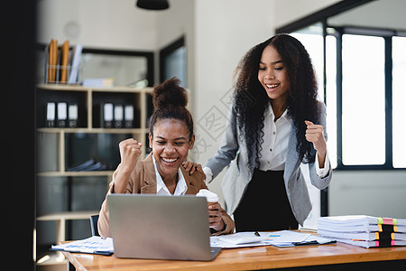 非洲妇女实现各种目标时激动人心 在办公室里用笔记本电脑举起手来欢欣鼓舞 新的启动项目概念商业企业家学生女孩经理技术商务男性工作男图片