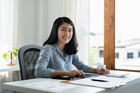 有吸引力的企业家亚洲女性的肖像 女商务人士在使用笔记本电脑从事会计财务工作时看着相机文书微笑女孩商业员工商务技术营销成人经理图片