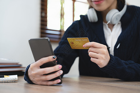 亚裔女孩在家购物时使用手机在线支付费用 在网上付款卡片银行零售店铺交易女性笔记本男人商业电子商务图片