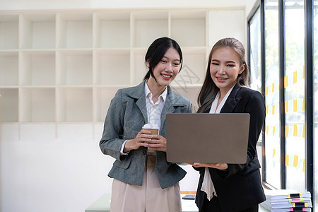 两名美丽的亚洲女商务人士利用数字平板电脑咨询和分析办公室工作的信息站立起来 她们站在办公室工作讨论团队女性工人商务女士合作企业家图片