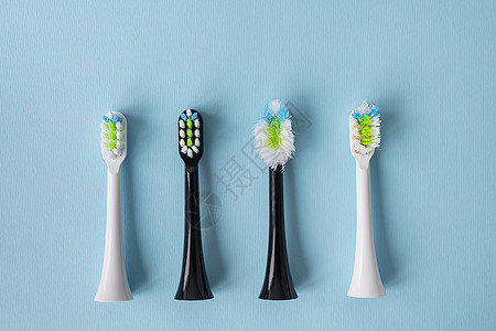 站在蓝色背景上的现代电动牙刷 是时候更换新旧刷头了 用于口腔日常护理的管制产品 卫生概念图片
