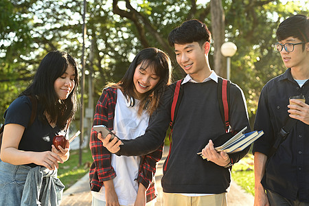 在大学校园户外放学后散步时 不同的年轻大学生朋友在与他人交谈时相互牵扯背景图片