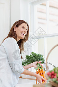 烹饪前先冲洗一下 一个美丽的女人在厨房水槽里 洗她刚捡到的胡萝卜图片