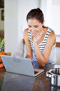 一位美丽的年轻女性浏览互联网 寻找她家的食谱 在网路上搜索食谱时电脑药片黑发蔬菜记事本厨房成人食物消耗品笔记本图片