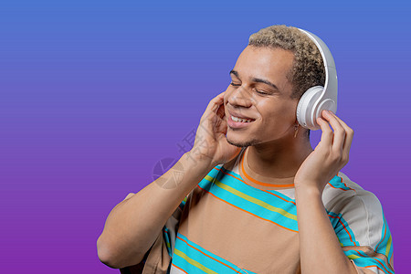 英俊的男人听音乐 在紫色工作室背景下戴着耳机享受舞蹈 收音机 无线现代音响技术 在线播放器图片