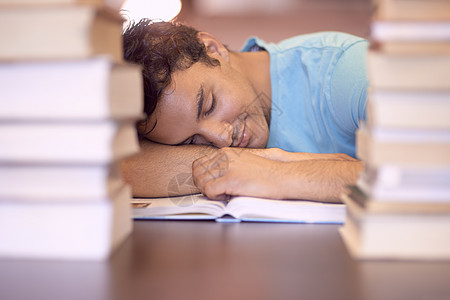 考试疲劳症 一个年轻学生在辛苦的学习课后睡在他的桌子上背景图片