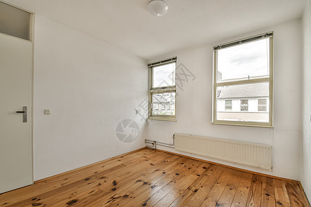 一个有木地板和两个窗户的起居室地面家具椅子地毯木头房子地板沙发客厅角落图片