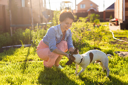 年轻女性在后院的草地上与她的狗玩耍 动物和友谊或宠物拥有者和爱的概念快乐家庭公园笑声阳光朋友女孩感情小狗自由图片