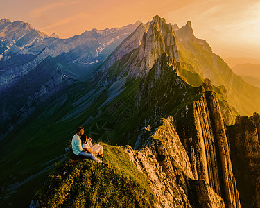 一对夫妇在山丘的日落中 观看Alpstein山脊图片