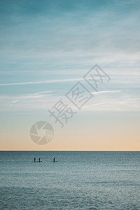 清晰的无云天空和平静的海洋相交的地平线 在远处 有人用划桨冲浪者手握着划桨的脚影图片