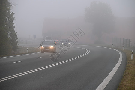 汽车在雾中的路上 秋季景观冬季危险的道路交通挡风玻璃运动阴霾大灯预报速度街道头灯下雨车辆图片